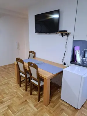 a dining room table with chairs and a television on the wall at Apartman Bubic in Banja Vrućica