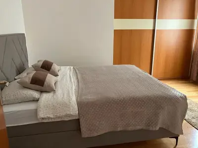 a bedroom with a bed with a wooden door at Stan na dan Centar Banja Luka in Banja Luka