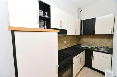 a kitchen with white cabinets and a black stove at Apartman centar blizina Kastela i Splava in Banja Luka