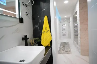 a bathroom with a white sink and a yellow towel at Villa Vidovic Banja Luka in Banja Luka