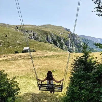 a person sitting on a swing in a field at Hotel Villa Ugar Vlašić in Vlasic
