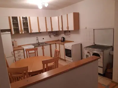 a small kitchen with a wooden table and a refrigerator at Apartman Laura in Kupres