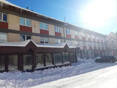 a snow covered parking lot in front of a building at Apartman Laura in Kupres