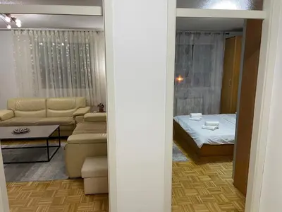 a room with a bed and a living room at Apartment Host in Tuzla