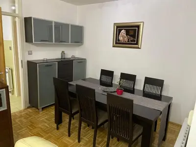 a kitchen with a dining room table and chairs at Apartment Host in Tuzla