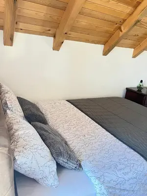 a bedroom with a bed with pillows and a wooden ceiling at Bajka na dan two bedroom apartment in Bosanska Gradiška