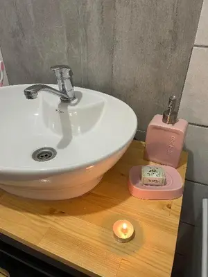 a bathroom with a sink and a candle on a wooden counter at Bajka na dan two bedroom apartment in Bosanska Gradiška