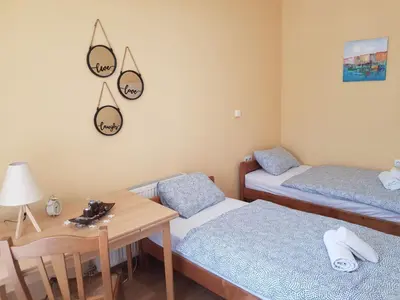 a room with two beds and a table and a desk at Apartment Studenac in Banja Luka