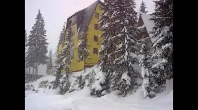 a large yellow building in the snow with trees at Sandy Vlašić in Vlasic