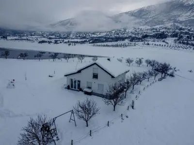 a house in a snow covered field with a mountain at Vikendica Bruše in Jaklići