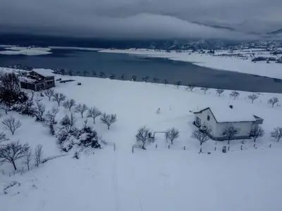 a house in the snow next to a body of water at Vikendica Bruše in Jaklići