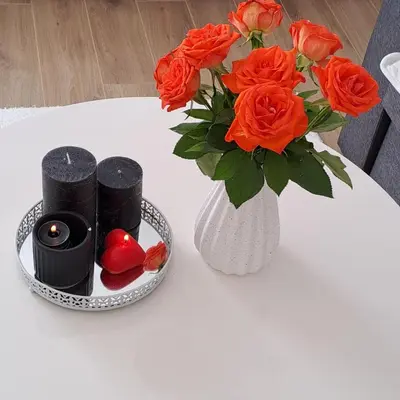 a white table with a vase of orange roses and candles at Vikendica Bruše in Jaklići