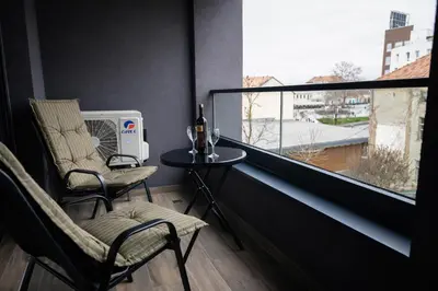 a balcony with two chairs and a table and a window at Muki Park Lake in Tuzla