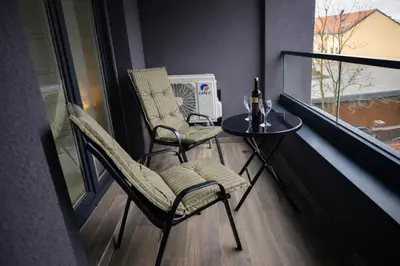 a balcony with two chairs and a table and a window at Muki Park Lake in Tuzla