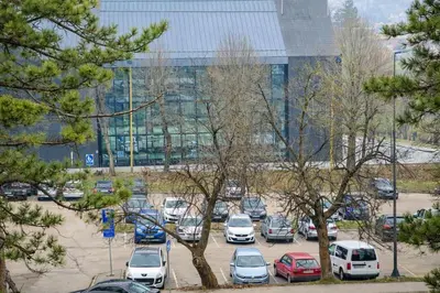 a parking lot with cars parked in front of a building at Muki Park Lake in Tuzla