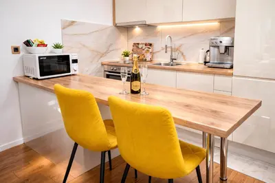 a kitchen with a wooden table and yellow chairs at Muki Park Lake in Tuzla