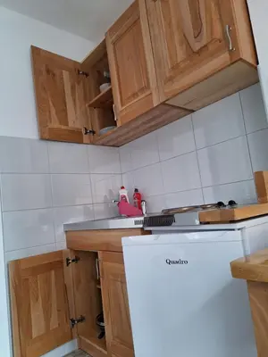 a kitchen with wooden cabinets and a white refrigerator at Apartmani 