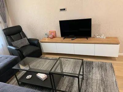 a living room with a tv and a chair and a table at Park Lake Suite in Tuzla