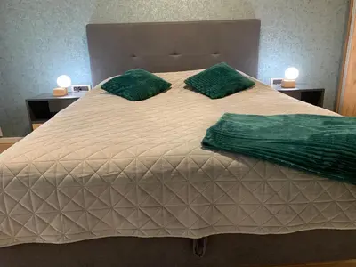 a large bed with two green pillows on it at Park Lake Suite in Tuzla