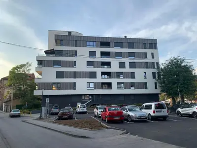 a parking lot with cars parked in front of a building at Park Lake Suite in Tuzla