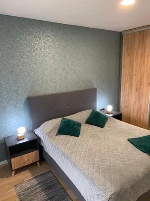 a bedroom with a bed with two green pillows at Park Lake Suite in Tuzla
