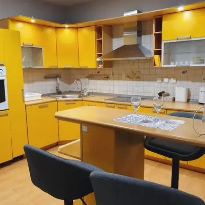 a kitchen with yellow cabinets and a table with two wine glasses at Apartments Arna in Visoko