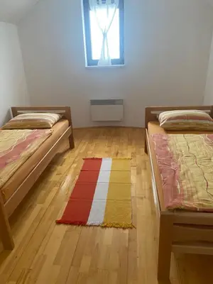 a room with two beds and a rug on the floor at Kuća za odmor Ivana in Kupres