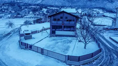 a house is covered in snow with a tree at Vikendica Bošnjak in Prozor