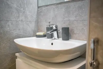 a bathroom sink with a faucet on top of it at Apartman EpiLux in Tuzla