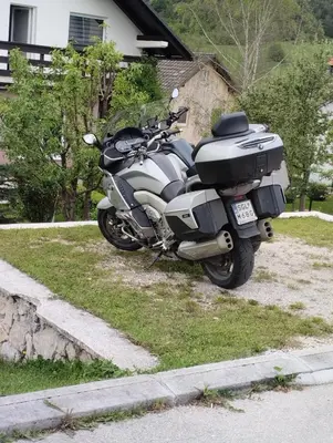a motorcycle parked on the grass in front of a house at Apartman Suzana in Kupres