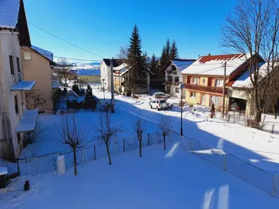 a snow covered street in a town with houses at Apartman Antonia in Kupres