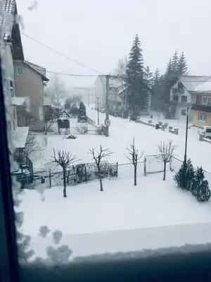 a snow covered yard with trees and buildings at Apartman Antonia in Kupres