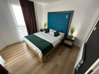 a bedroom with a large bed with a blue headboard at Business Hotel Prijedor in Prijedor