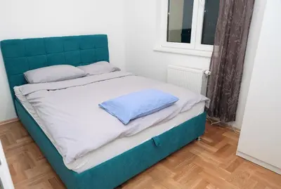 a bed with a blue headboard in a room at Apartman Venezia in Banja Luka
