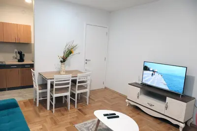 a living room with a tv and a table with chairs at Apartman Venezia in Banja Luka