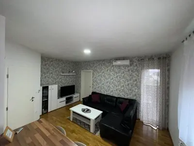 a living room with a black couch and a table at Apartman Giljen in Teslić