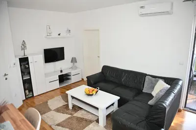 a living room with a black leather couch and a table at Apartman Giljen in Teslić