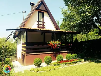 a small house with flowers in a yard at Holiday Home Ravne in Visoko