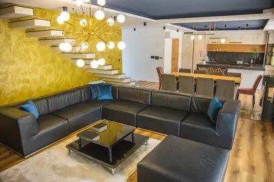 a living room with a leather couch and a staircase at Lohovo Villa Bukva in Otoka