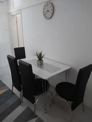 a dining room table with chairs and a clock on the wall at Apartman Aladin in Bihać