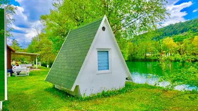 a small house with a green roof next to a lake at Una Kamp in Bosanska Krupa