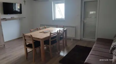 a wooden table and chairs in a living room at Apartmani Čiča in Kupres