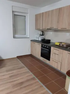 a kitchen with wooden cabinets and a black stove at Apartmani Čiča in Kupres