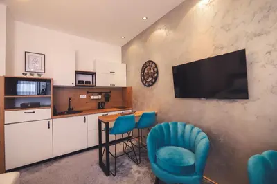 a kitchen with a table and chairs and a television on a wall at Central Square Apartment in Banja Luka