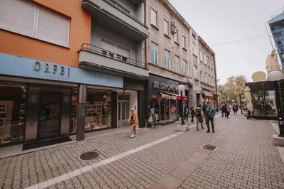 a group of people walking down a street with buildings at Central Square Apartment in Banja Luka