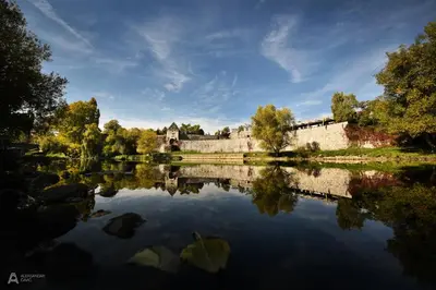 a castle is reflected in the water of a lake at Central Square Apartment in Banja Luka