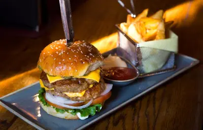 a hamburger on a plate with a basket of fries at Apartmani Di Casa Dreams in Donji Vakuf