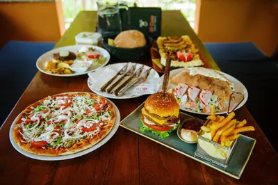 a wooden table with plates of food and a pizza and french fries at Apartmani Di Casa Dreams in Donji Vakuf