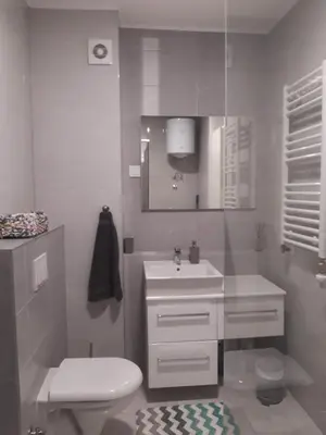 a white bathroom with a toilet and a sink at Elena apartmani Tuzla in Tuzla