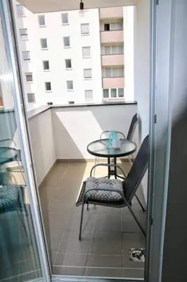 a table and chair on a balcony with a window at Elena apartmani Tuzla in Tuzla